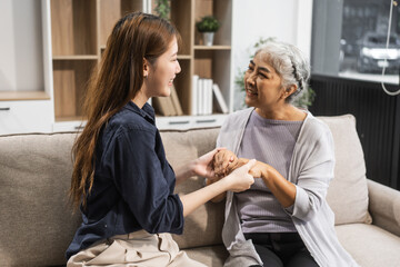 A mature mom and her young daughter, both Asian, sit on sofa, celebrating Mother's Day. They share comfort, closeness, warmth, embracing their bond with tenderness, laughter, and cherished memories.