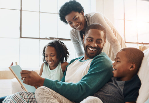 Reading, happy and black family with book on sofa for bonding together on fathers day at home. Smile, knowledge and African parents relaxing with children in living room with fantasy story or novel. - Powered by Adobe