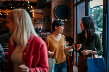 Fototapeta premium Smiling women with shopping bags entering a trendy restaurant, excited for a meal together