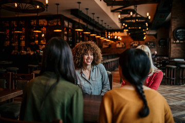 A multiracial group of young people sitting in a coffee shop and smiling