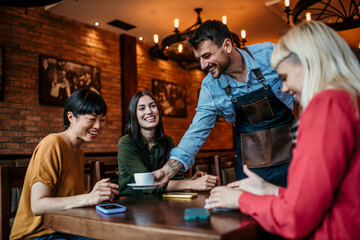 Image of a waiter delivering drinks to a group of females at a restaurant