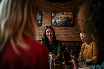 Four Young Female Friends Meeting Sit At Table In Coffee Shop And Talk