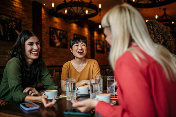 Group of women at the cafe, talking, smiling, laughing, and enjoying their time. Lifestyle and friendship concepts with real people models