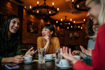 A group of women at the cafe, talking, smiling, laughing, and enjoying their time. Lifestyle and friendship concepts with real people models