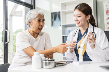 Obraz premium A young Asian female nurse providing healthcare services at her desk, caring for an elderly woman patient. They discuss health checklists and medical advice in a professional setting.
