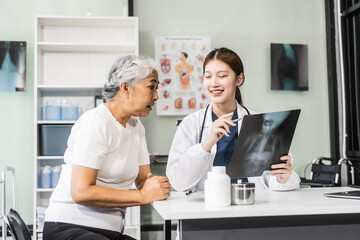 Obraz premium A young Asian female nurse providing healthcare services at her desk, caring for an elderly woman patient. They discuss health checklists and medical advice in a professional setting.