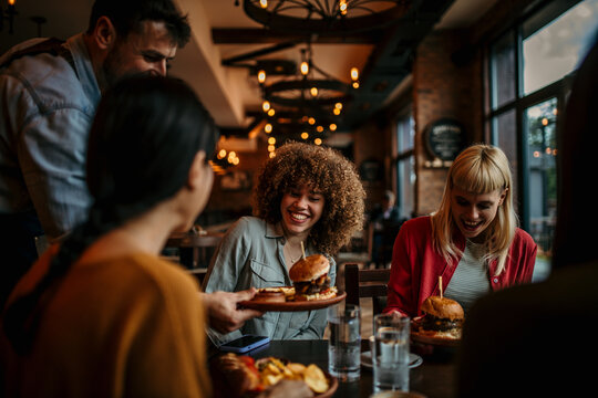 Waiter serving food to a group of customers at a restaurant