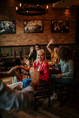 Fototapeta premium Group of a smiling female friends having a lunch together and being photograph by the waiter