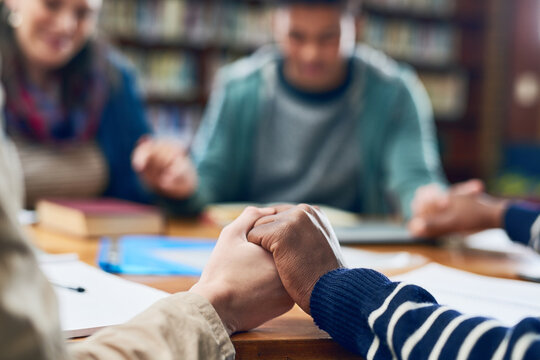 Students, friends or holding hands in prayer in library for blessings, grace or guidance in college. Closeup, people and hope with spirituality for thanks, school or teamwork in study group for exams