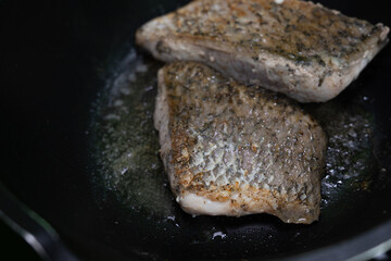 Fresh sea bass marinated with spices and fried with butter in a black iron pan.