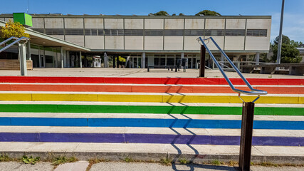 Colorful rainbow-painted staircase leading to a modern building, symbolizing LGBTQ+ pride and...