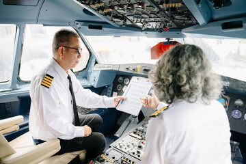 Mature commercial male pilot Beautiful middle aged woman airplane captain instructor has a meeting,...