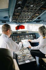 Mature commercial male pilot Beautiful middle aged woman airplane captain instructor has a meeting, discussion with aircrew team © Nuttapong punna