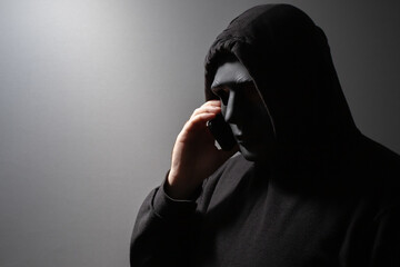 Robber, a man in a mask talking on the phone, thief planning burglary, criminal discussing crime,...