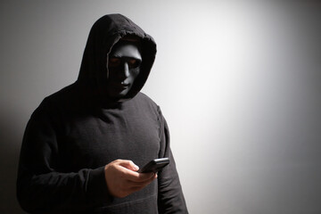 Man in a mask with a phone, hacker, scammer, spy.