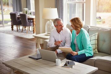 Senior couple, paperwork and finance on sofa with laptop, smile and talk for profit in home. Old...