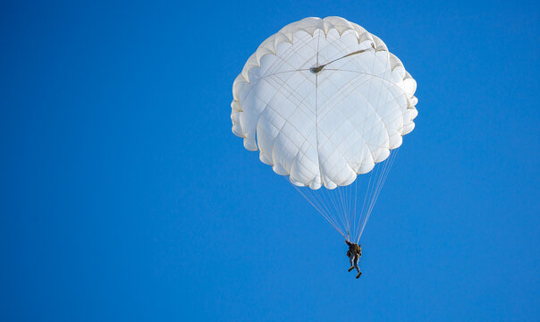 Skydiving. Flying parachutists against the background of the blue sky and mountains. Extreme sport and entertainment.