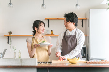 キッチンで料理をする夫婦・包丁で野菜を切る男性
