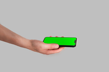 Hand holding smartphone. Clean empty touch green screen. White background.