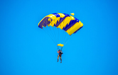 Skydiving. Flying parachutists against the background of the blue sky and mountains. Extreme sport and entertainment.