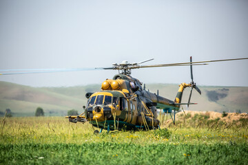 In the field is a military helicopter with soldiers. Armed conflict, fighting. Air armament and...