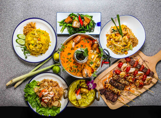 spicy tom yam soup king shrimps, yellow chicken curry, fried chinese kale with pork belly, thai fried noodles with shrimp, beef satay, skewer, pineapple rice, pomelo salad assorted food honk kong