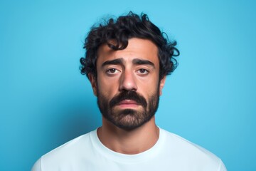 Obraz premium Sad man, 34, Middle Eastern, feeling insecure, on a pastel blue background