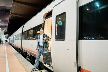 young traveller getting off a train in a station