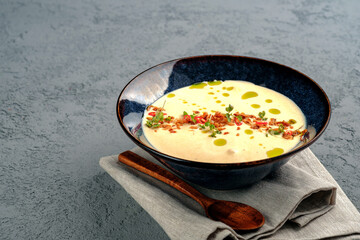 Cheese soup with bacon and potatoes garnished with herbs, pepper