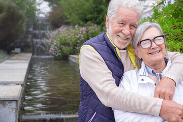 Happy mature couple in love embracing outdoor in the park, grey haired husband and wife smiling, family enjoying tender moment, happy marriage, sincere feelings