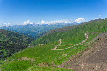 A winding mountain road leading to the Datvisjvari pass. View of the Chaukhi Mountains.