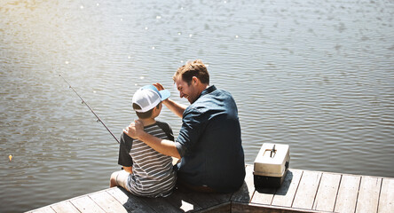 Father, back and bonding with son or fishing rod by lake, ocean or beach together in nature. Man...