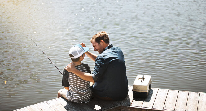Father, back and bonding with son or fishing rod by lake, ocean or beach together in nature. Man with young child, kid or little boy with hug for lesson or tips to catch sea creatures by water