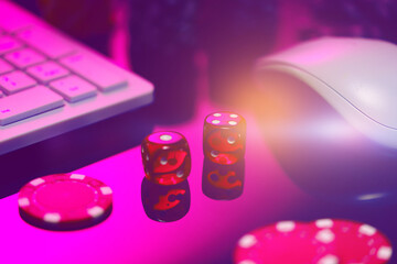 Red Dice on a Pink Surface With a Computer Keyboard and Mouse
