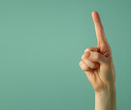 A hand is raising its index finger in a photo in front of a green background
