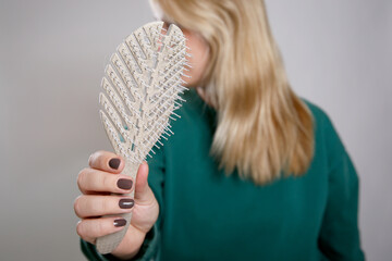 Close up portrait of a caucasian woman holding a beige brush, grey empty background 