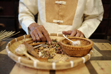 Close-up of worker of drug store selecting herbs and spices for Chinese therapy