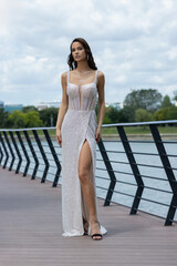Beautiful young bride in wedding dress posing by the river bank
