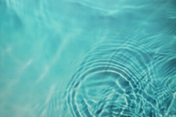a pool in which the water appears blue and a few waves are created by dripping water.