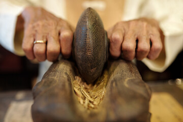Close-up of senior man grinding ginger in ancient way for traditional Asian medicine
