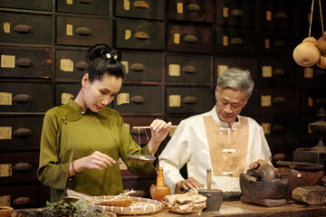 Medical workers working together with herbs in Asian old drug store