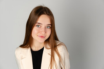 Obraz premium Young Woman in White Jacket and Black Pants on Gray Background.