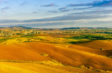 Fototapeta premium beautiful landscape in a yellow golden field in autumn or summer evening with nice rustic view of hills in countryside
