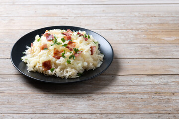 Slovak potato dumplings halusky with steamed sauerkraut and bacon on wooden table. Copy space