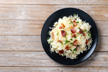Slovak potato dumplings halusky with steamed sauerkraut and bacon on wooden table. Top view. Copy space