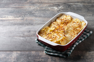 Potato gratin baked with cream and cheese on wooden table. Copy space