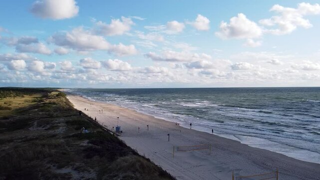 Aerial view of Pervalka Beach along the Baltic Sea in Lithuania, showcasing its expansive sandy shore, gentle waves, and scenic beauty under a partly cloudy sky.