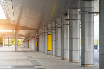 Rows of long white pillars support and strengthen the roof of a large building. Entrance group canopy for pedestrians under the bridge
