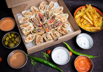 Turkish or Arabic Shawarma box full of pieces of chicken shawerma or shawarma wrap with onion, tomato, lettuce and garlic sauce in Syrian bread with side french fries and fried bread.