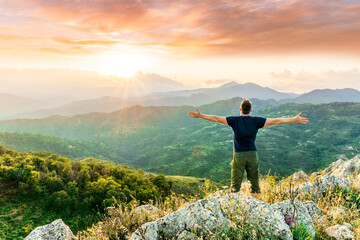 Obraz premium happy man watching amazing highland evening sunset, person delight with nature landscape